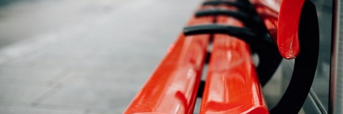 Red city benches on a sidewalk.