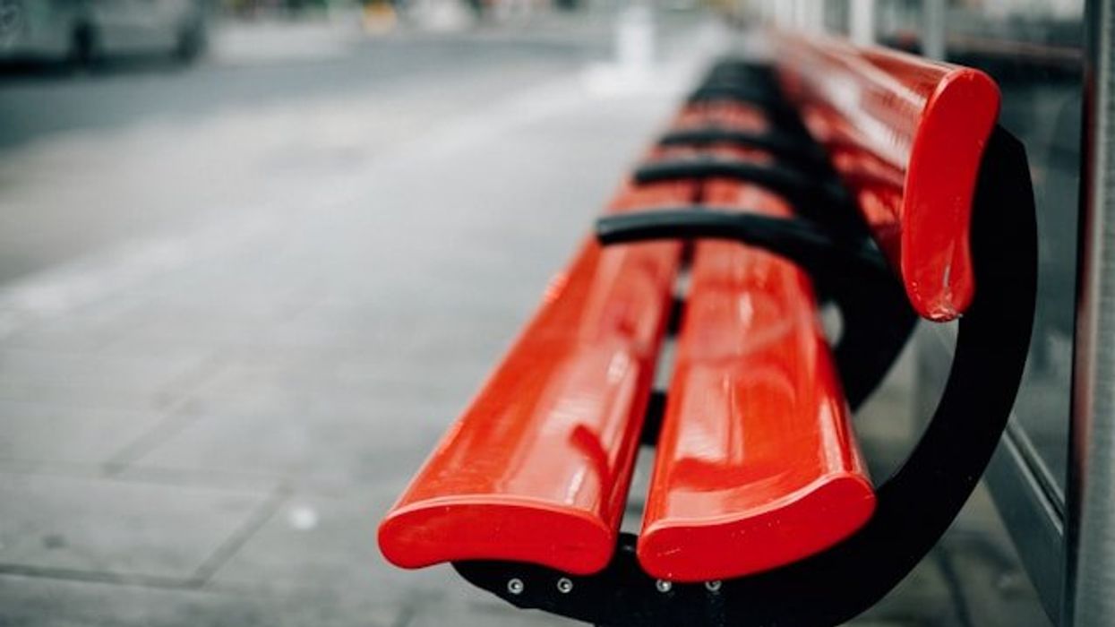 Red city benches on a sidewalk.