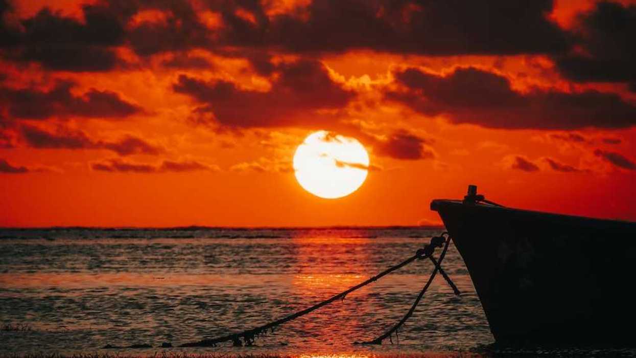 Red sunset over the ocean backlighting a tied-off skiff