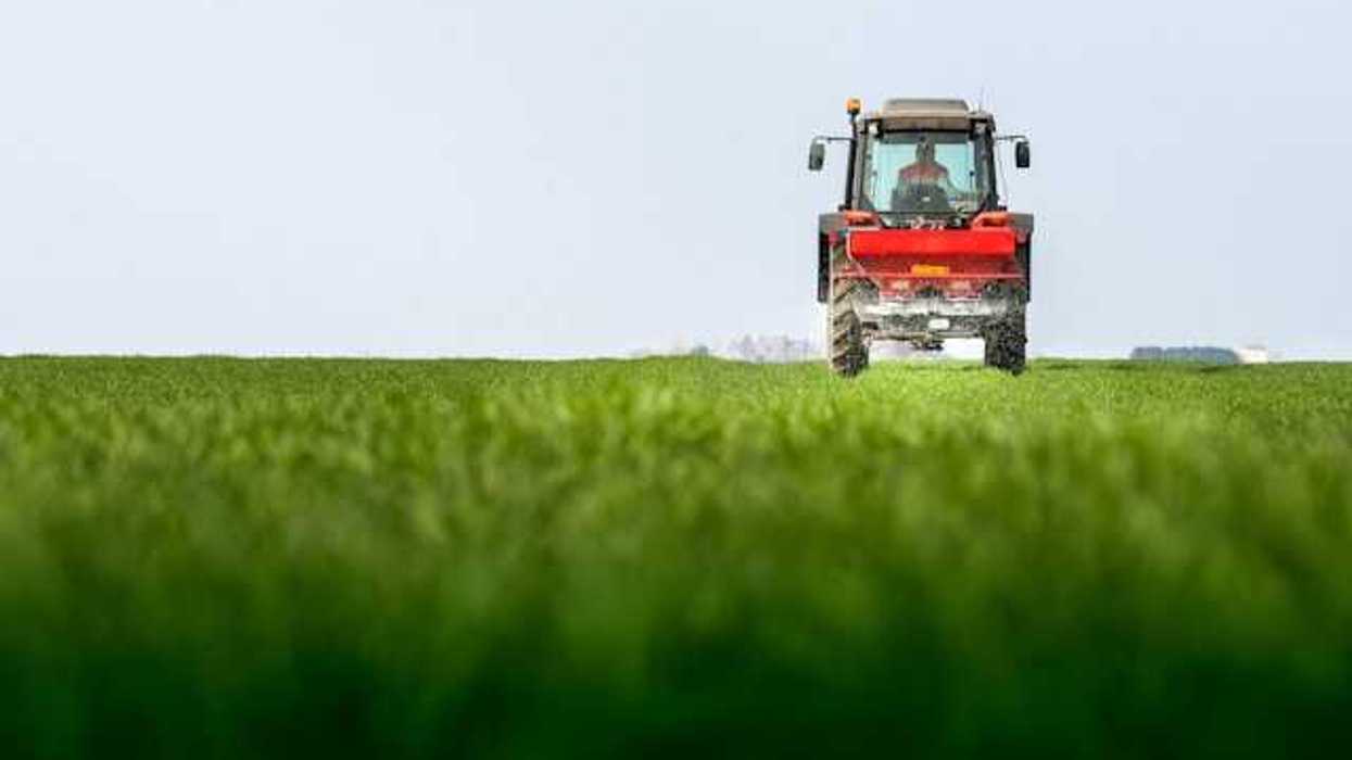 Red tractor driving on green field