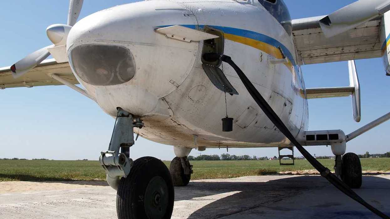 Refueling a white prop plane at an airfield