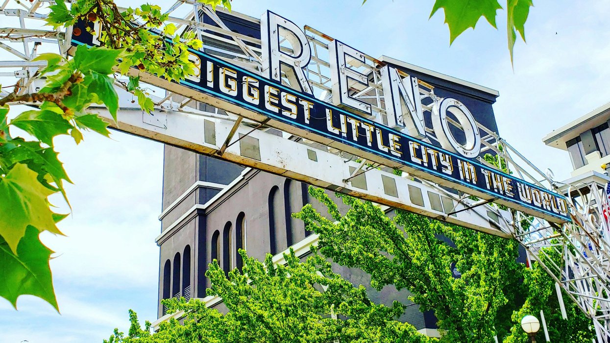 Reno arch sign with buildings and trees on a sunny day.