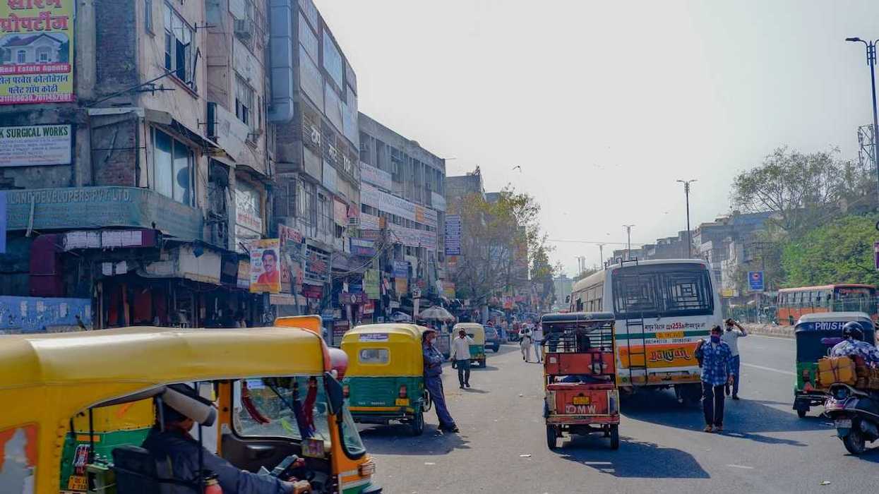 Rickshaws, scooters, busses, and pedestrians on a Delhi street