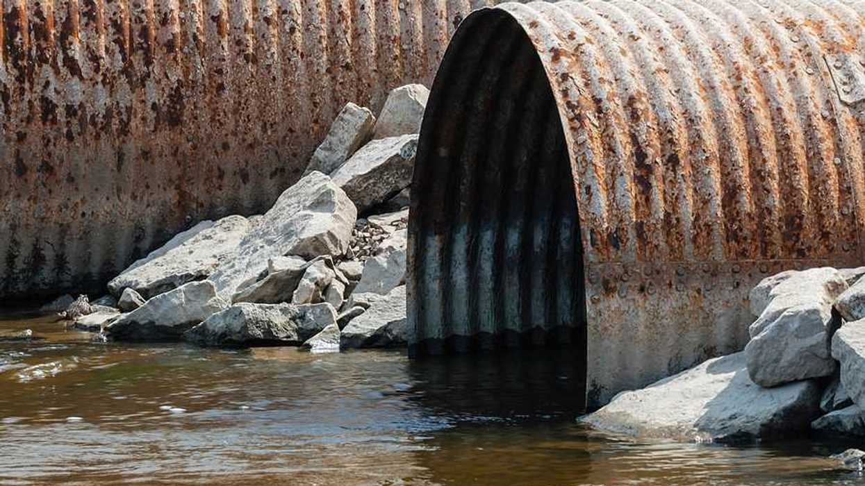 Rusty pipes emitting water into a stream
