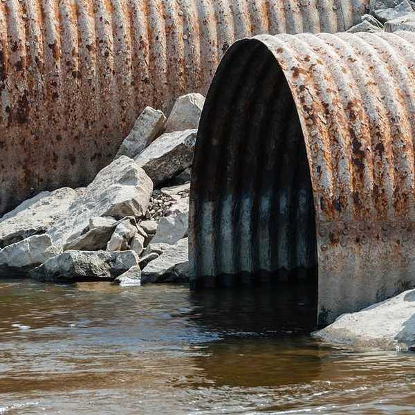 Rusty pipes emitting water into a stream