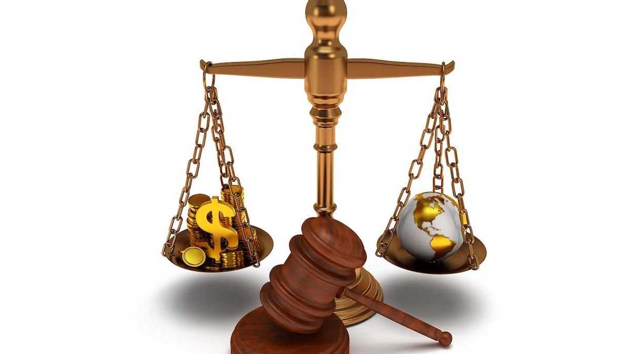 Scales of justice depicting wealth balanced against earth globe.