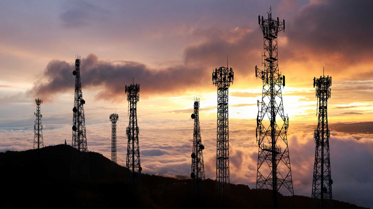Several cell towers on top of a hill at sunset