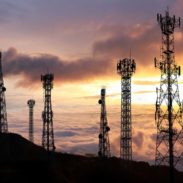 Several cell towers on top of a hill at sunset