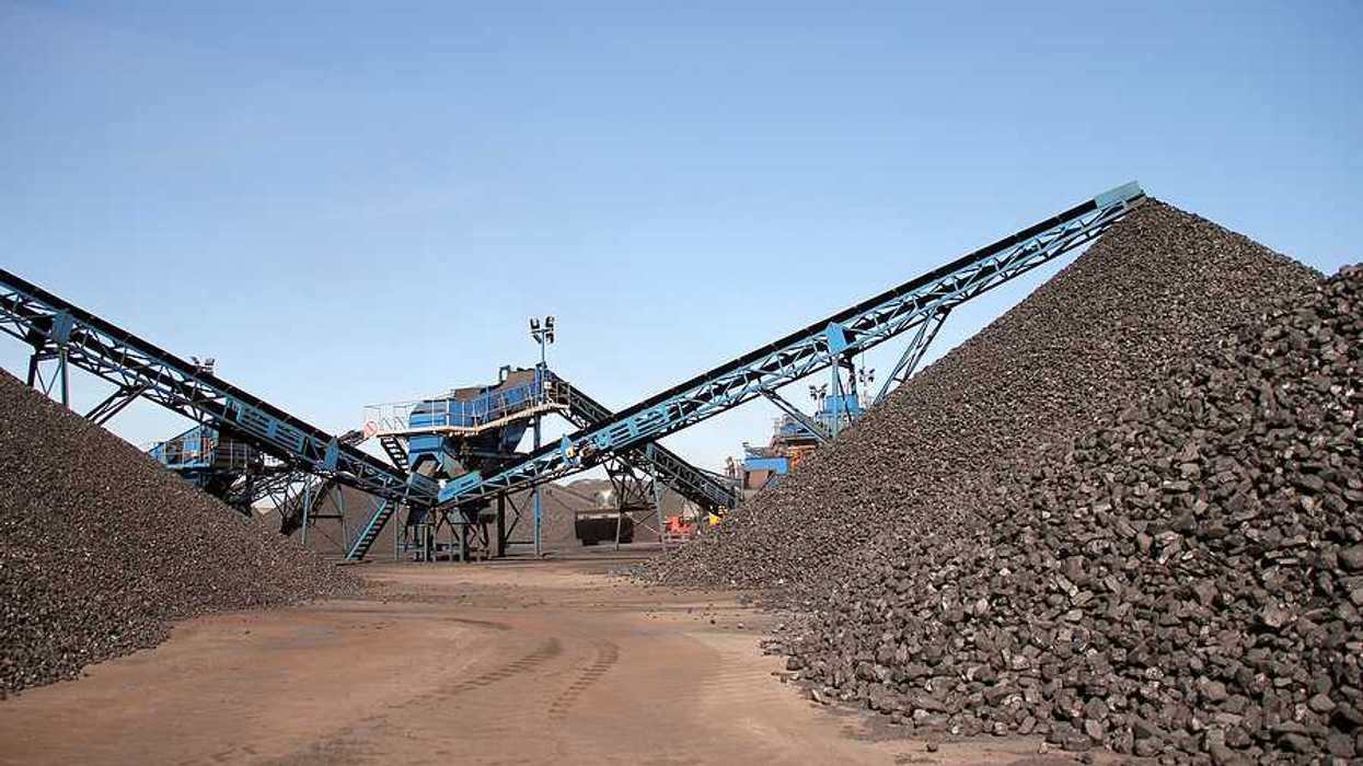 Several piles of coal with equipment in the background