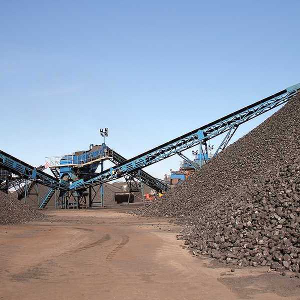 Several piles of coal with equipment in the background