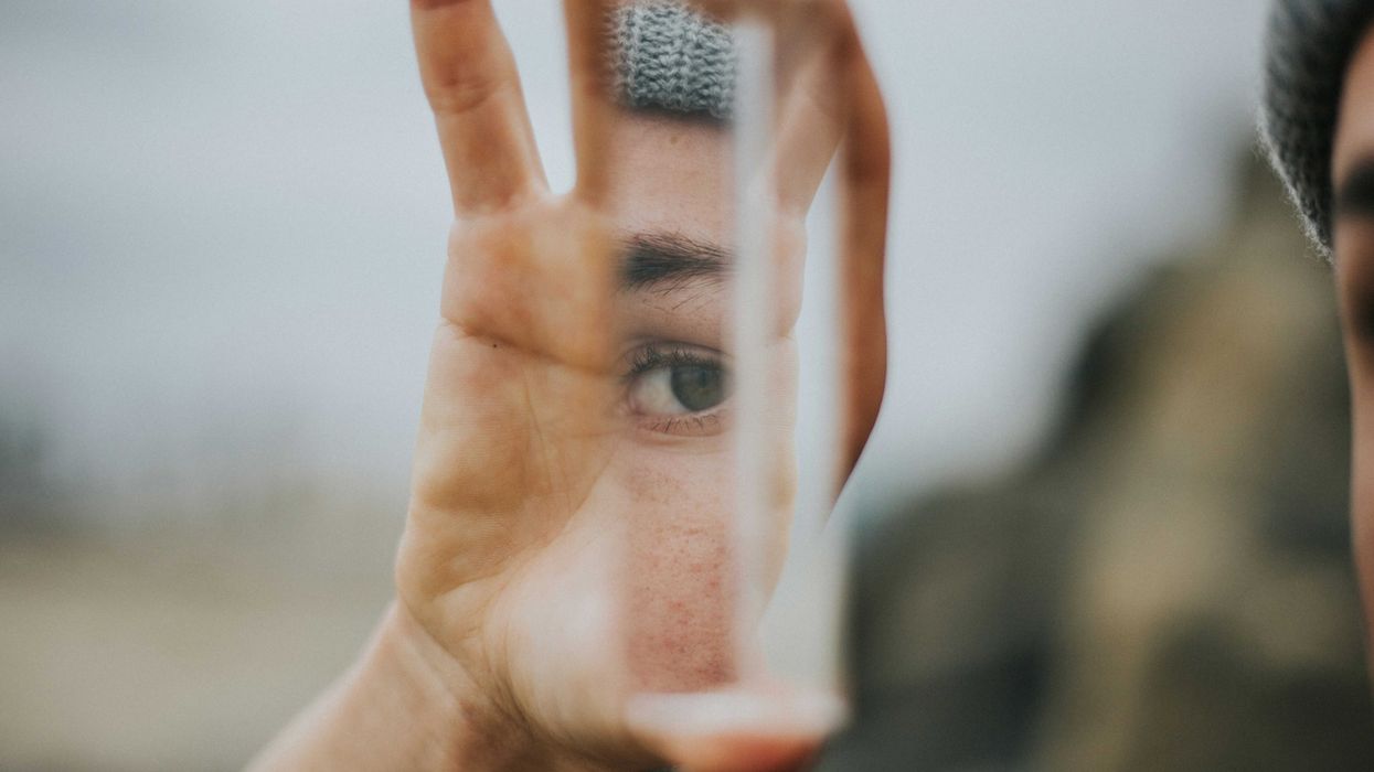 shallow focus of person holding a narrow mirror reflecting their eye.