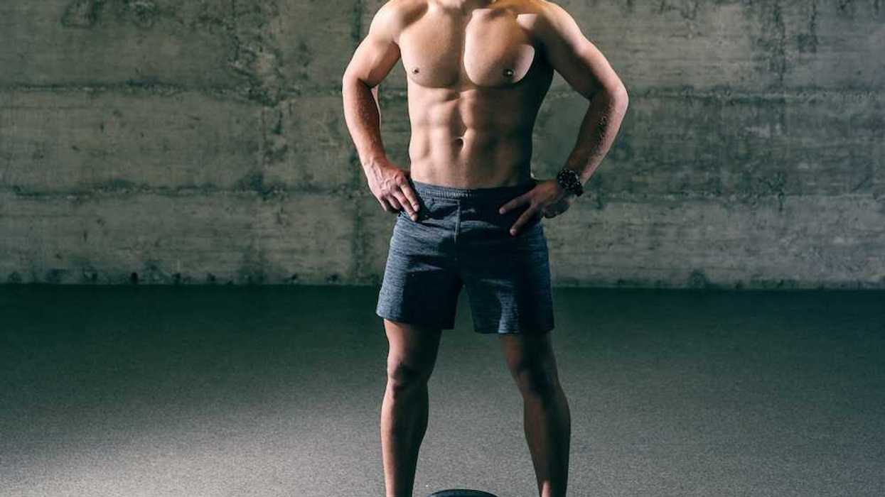 Shirtless man in athletic shorts standing over kettle ball
