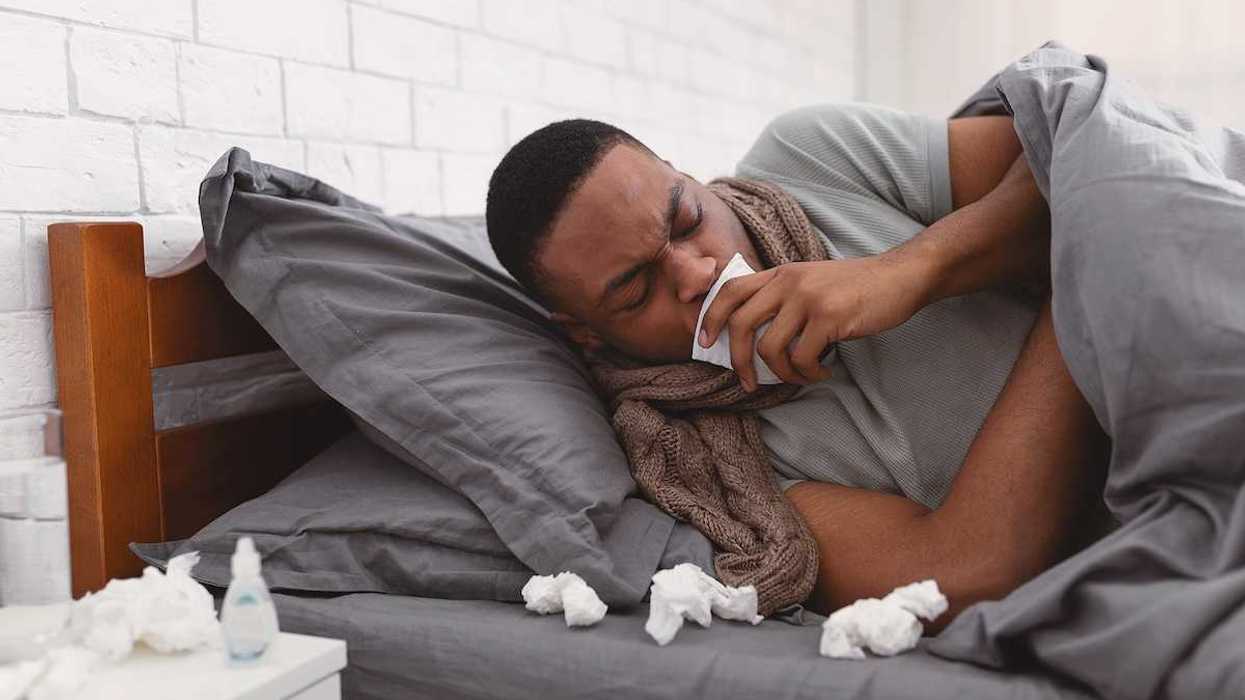 Sick African American man coughing holding paper napkin near mouth suffering from respiratory ailment