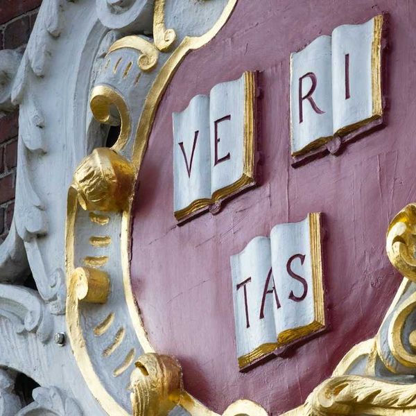 Sign on brick building at Harvard reads VE RI TAS