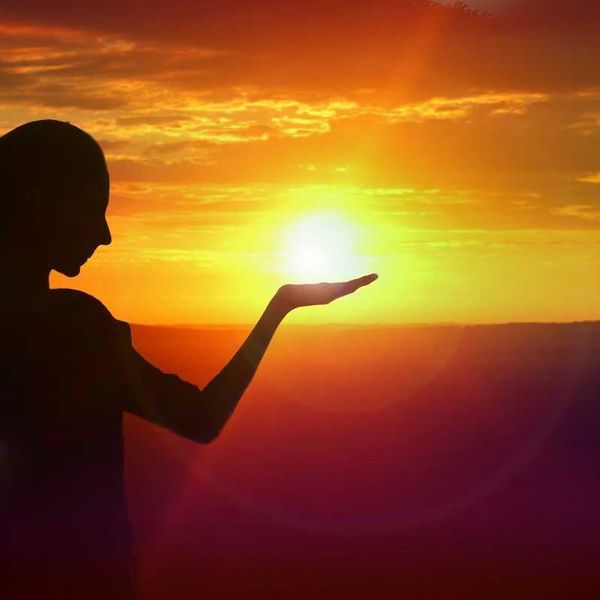 silhouette of a girl facing sunset, golden sky and water
