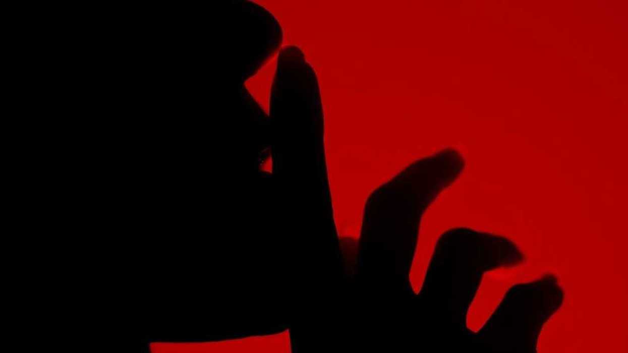 Silhouette of a person with finger to lips in a shushing gesture
