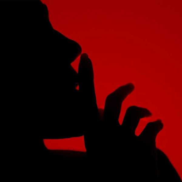 Silhouette of a person with finger to lips in a shushing gesture