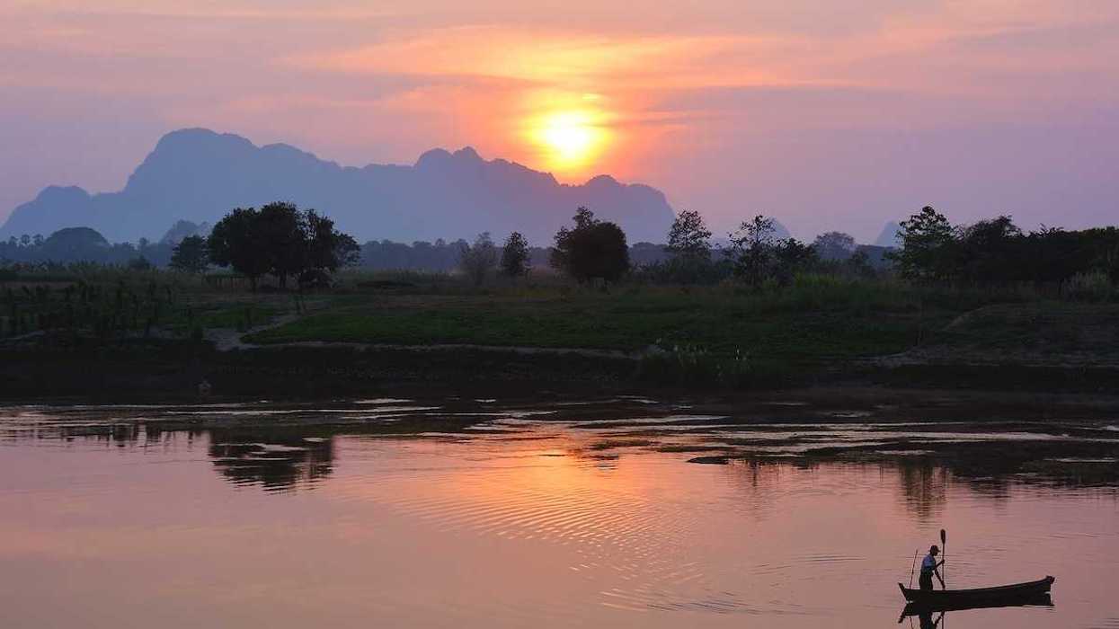Silhouette of asian fisherman floating in the boat at the sunset in Hpa-An Myanmar
