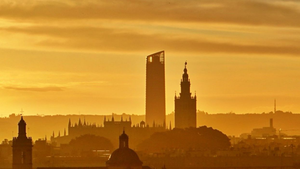 silhouette of buildings in Seville, Spain against a golden evening sky.