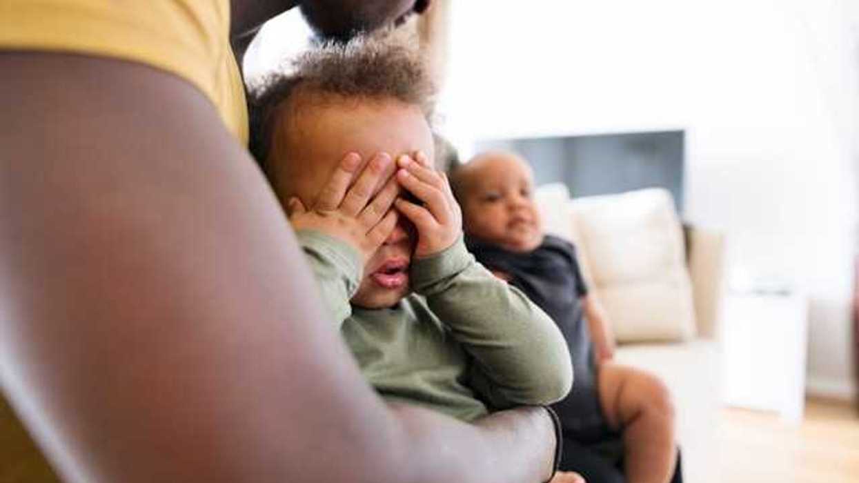Small Black child sitting his fathers lap covering his eyes