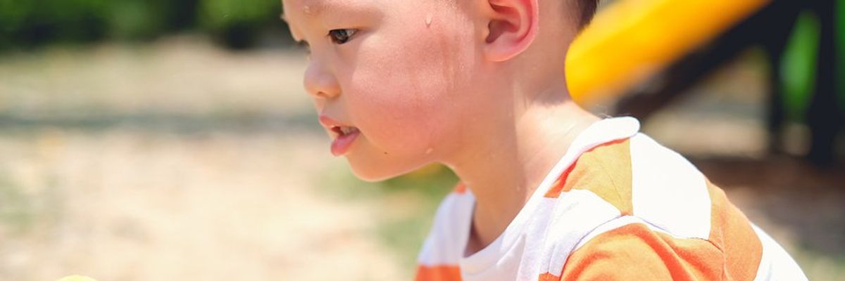 Small boy at a playground on a hot day.