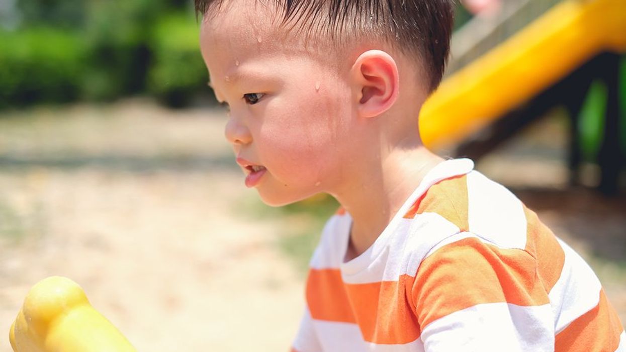 Small boy at a playground on a hot day.