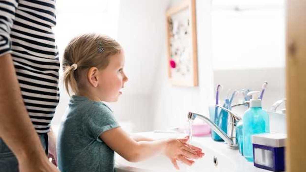 Small girl standing at bathroom sink washing her hands