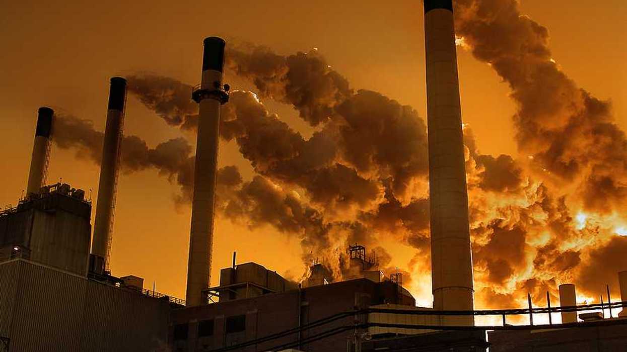 Smoke billowing out of smokestacks against an orange sky