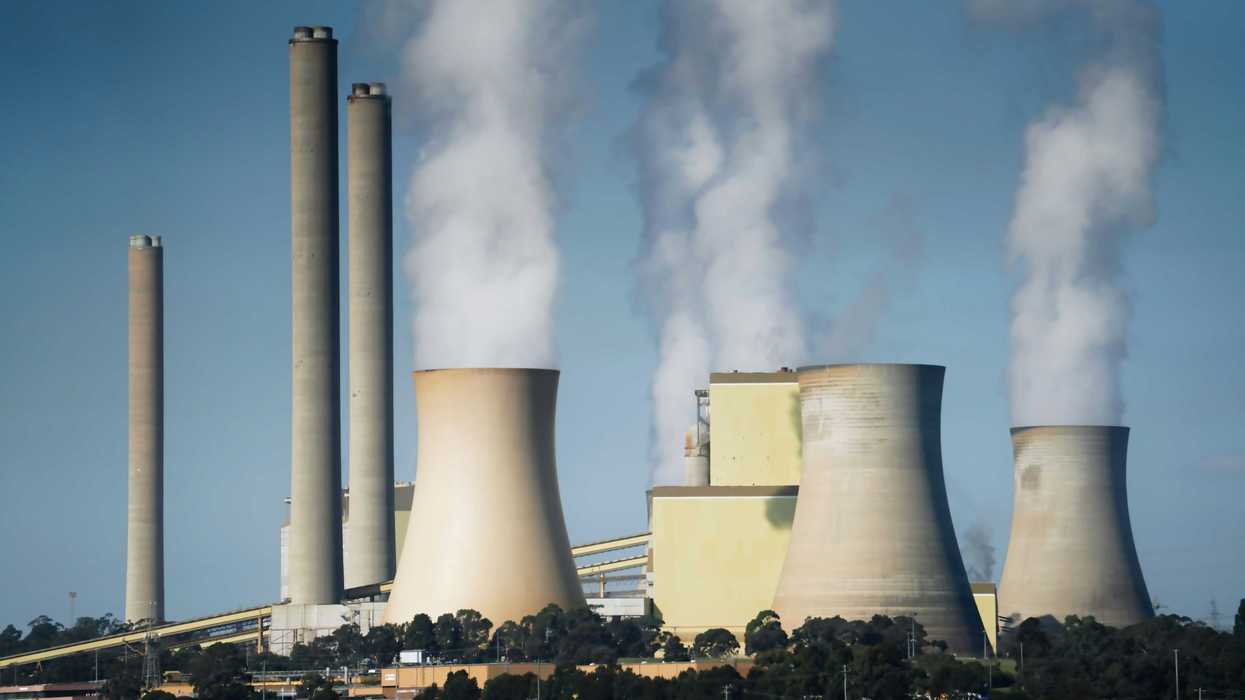 smoke billows from the cooling towers of a power plant.