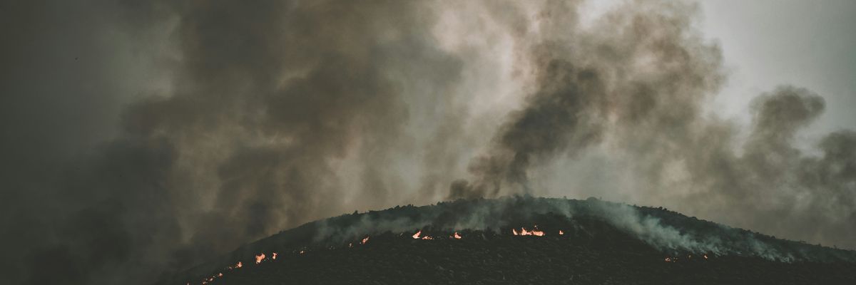 smoke billows over a mountainside wildfire
