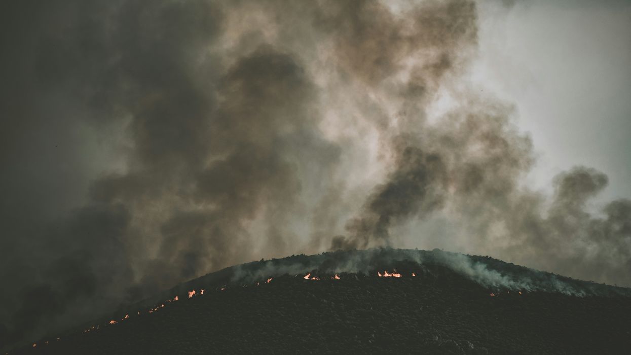 smoke billows over a mountainside wildfire
