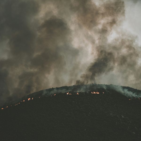 smoke billows over a mountainside wildfire
