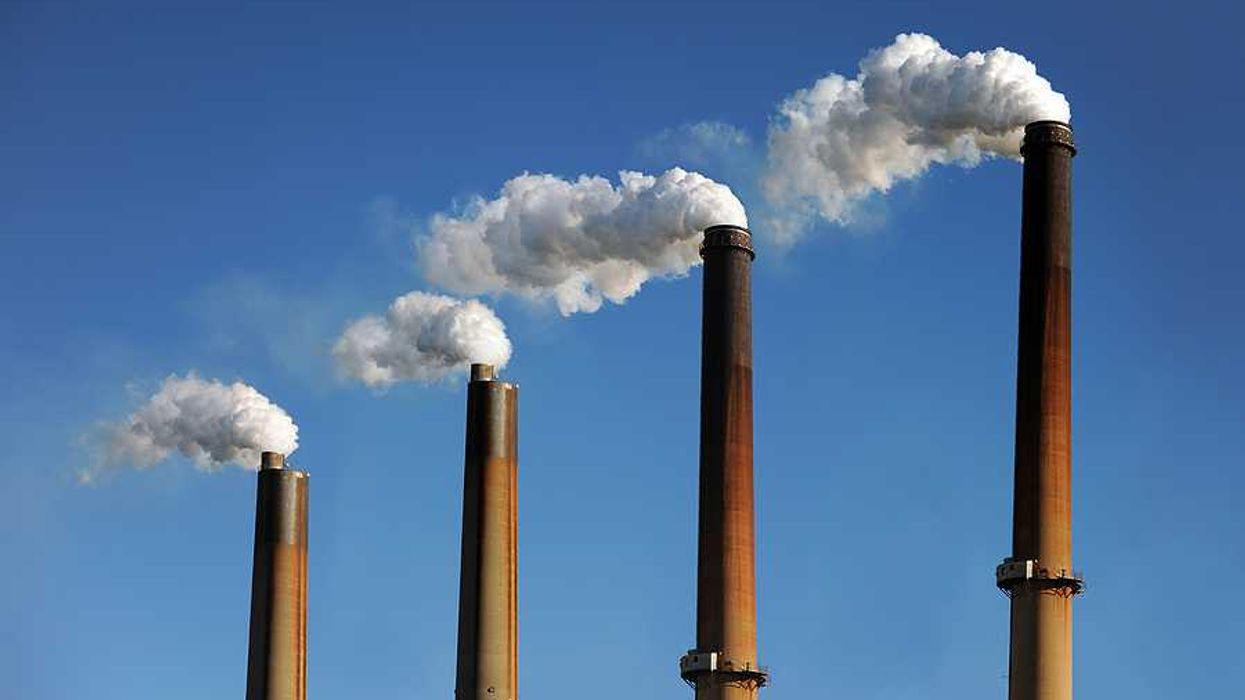 Smokestacks emitting smoke against a blue sky