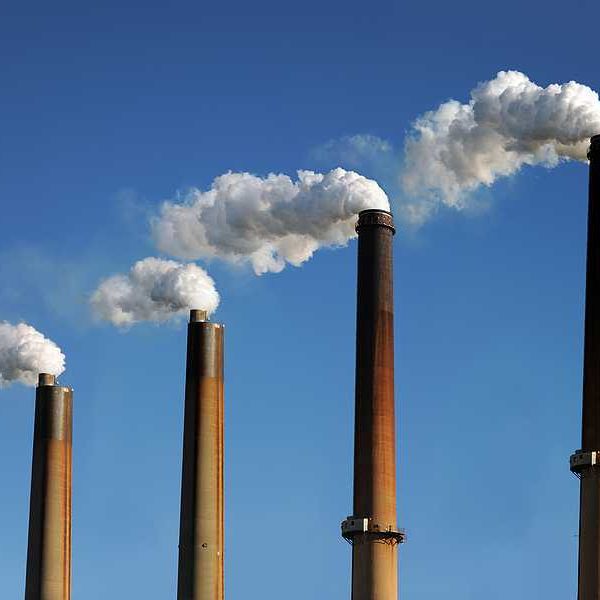 Smokestacks emitting smoke against a blue sky