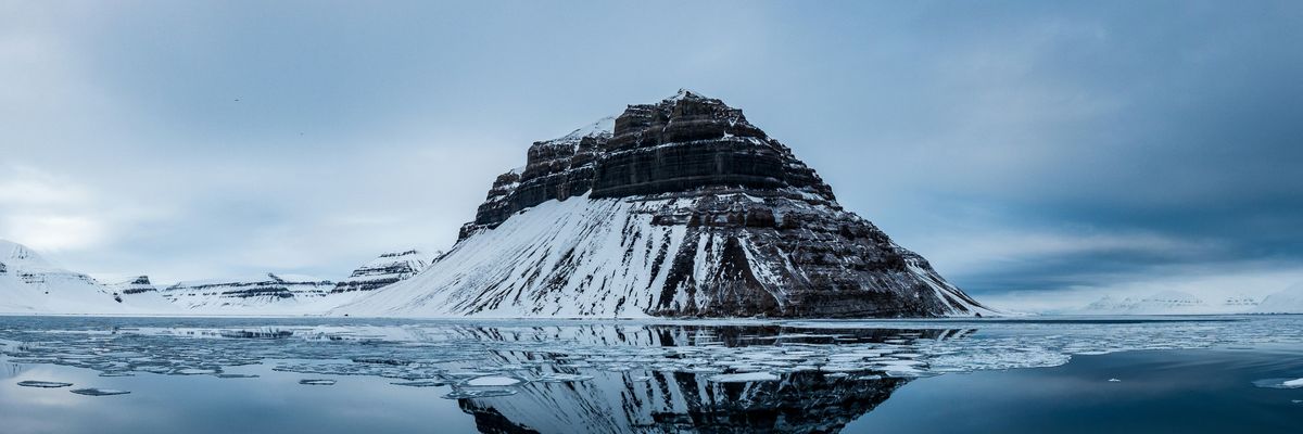 Snow covered mountain near body of water.
