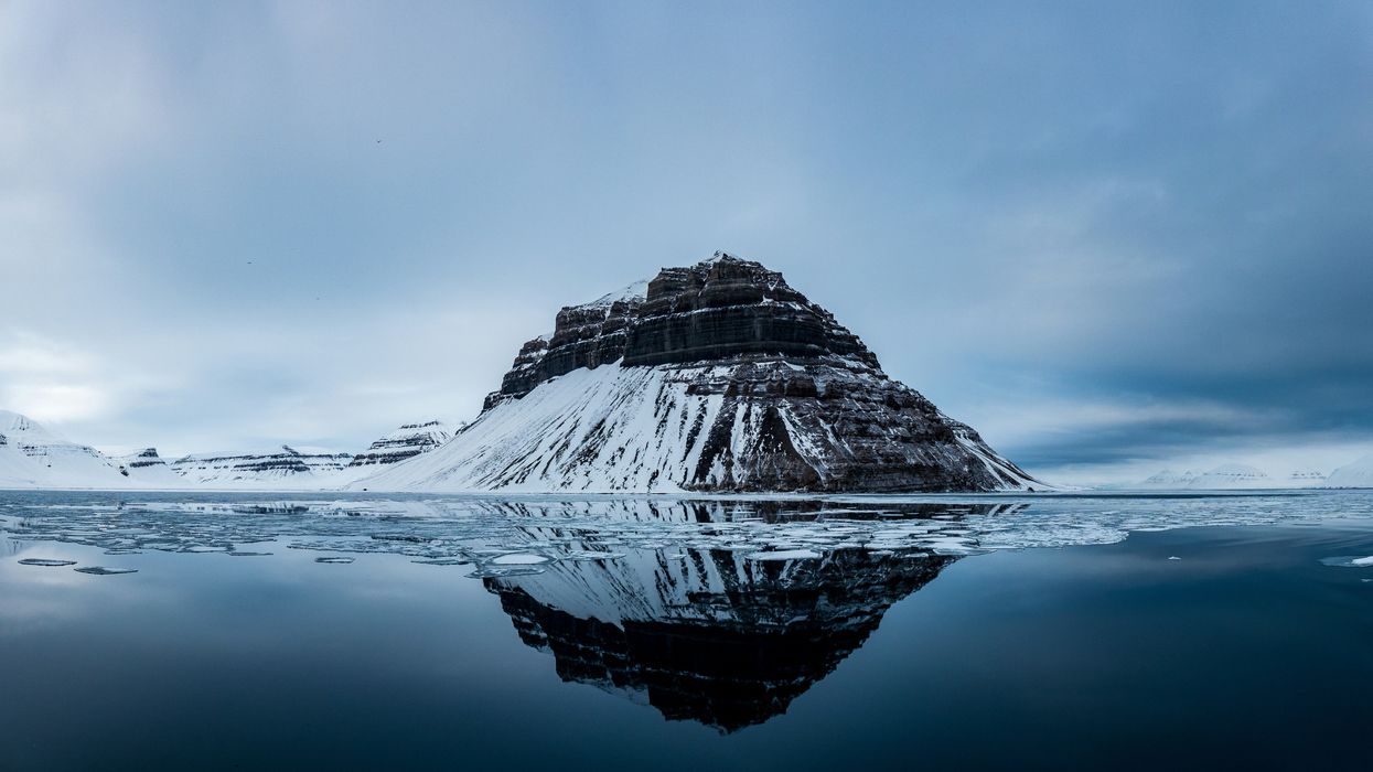 Snow covered mountain near body of water.