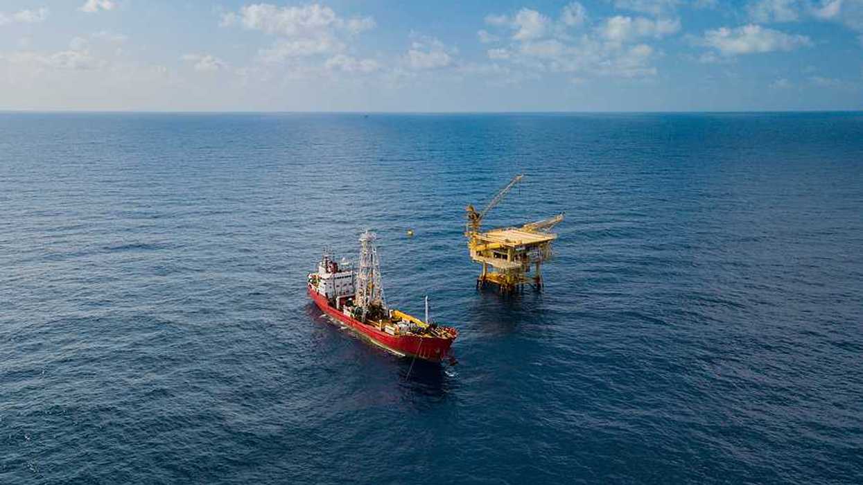 Soil Boring Boat aka survey vessel close to an oil platform in open ocean.