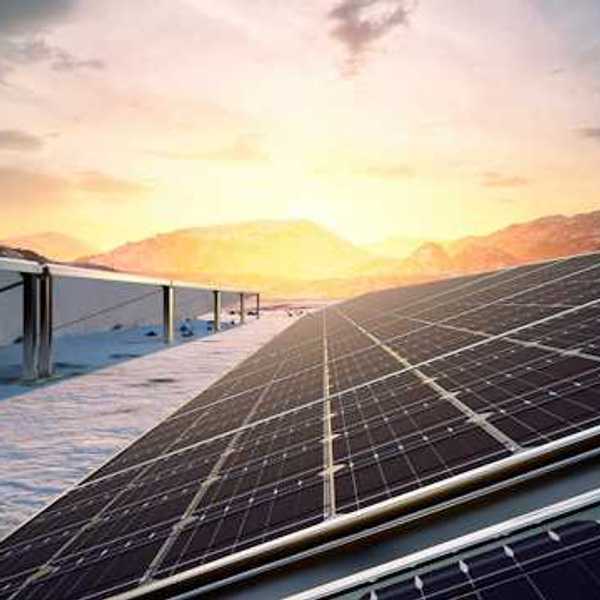 Solar panels in a snowy landscape with mountains in the background