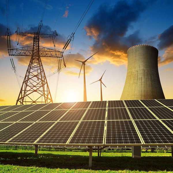 Solar panels in the background nuclear power plant, wind turbines and electricity pylon at sunset.