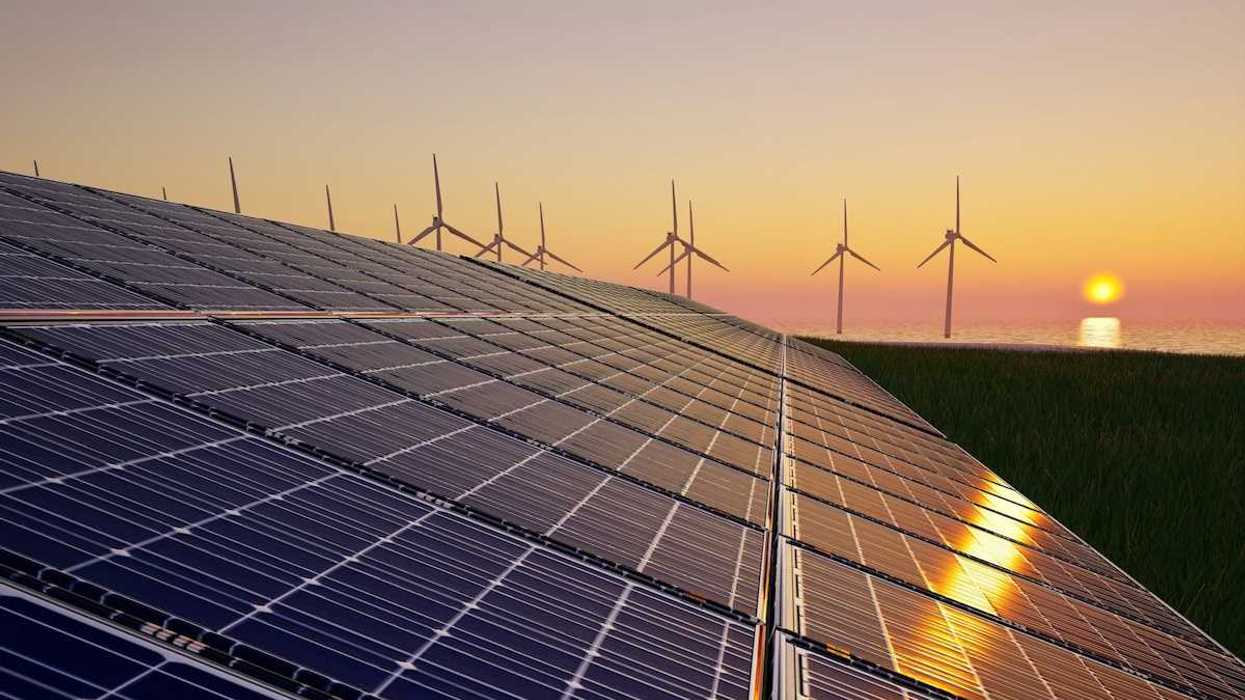 Solar panels & wind turbines against setting sun