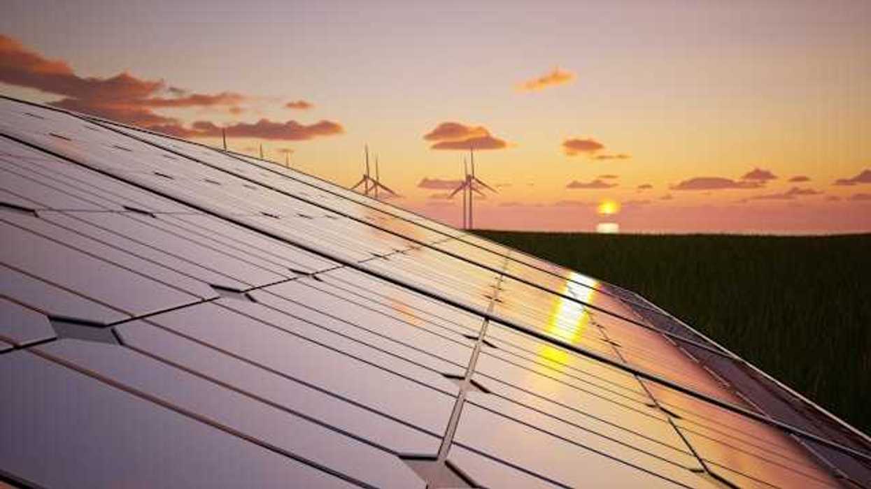 Solar panels with wind turbines and a setting sun in the background