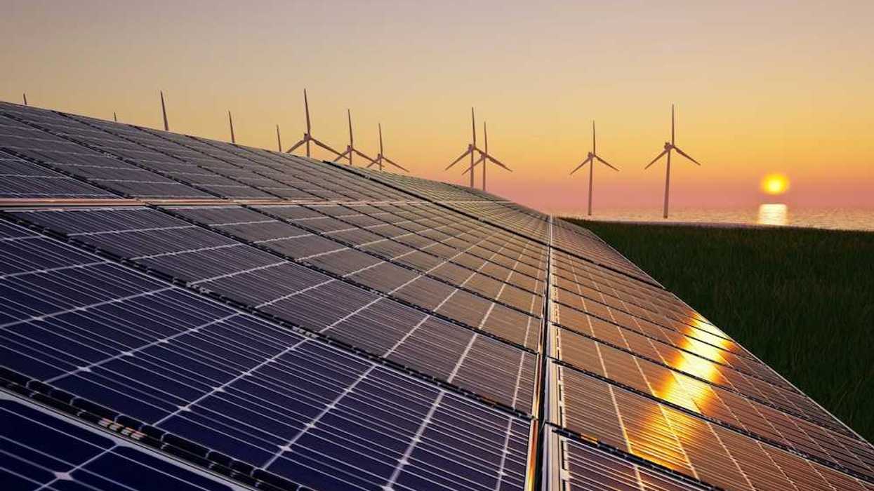Solar panels with wind turbines in the background