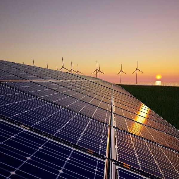 Solar panels with wind turbines in the background