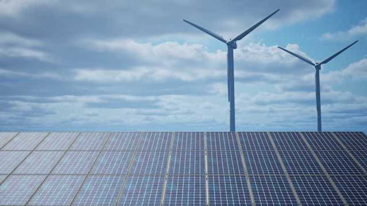 Solar panels with wind turbines in the background