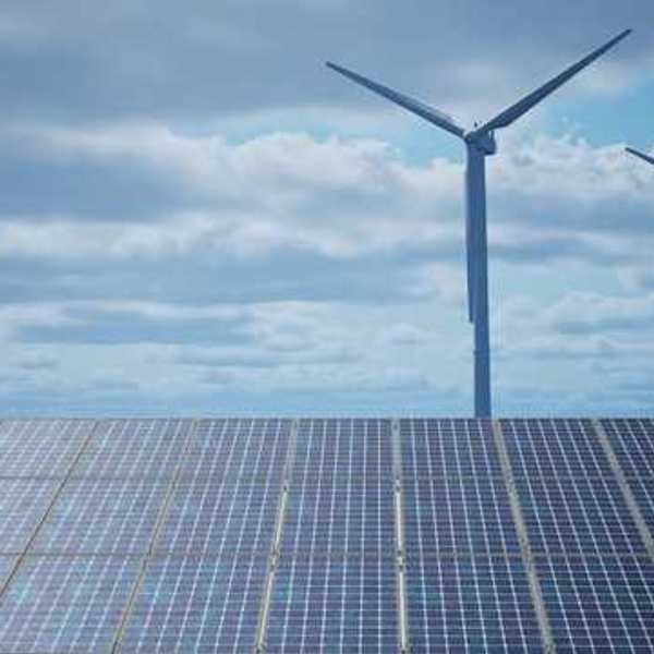 Solar panels with wind turbines in the background