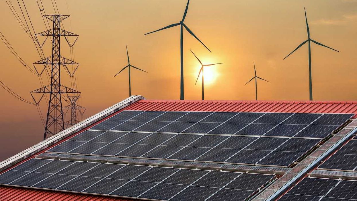 Solar power panels on a roof with wind turbines and powerlines behind