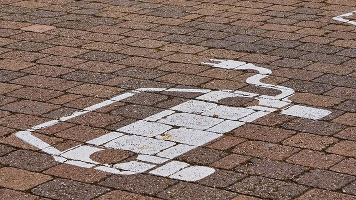 Stencil of an electric vehicle on a brick pavement.