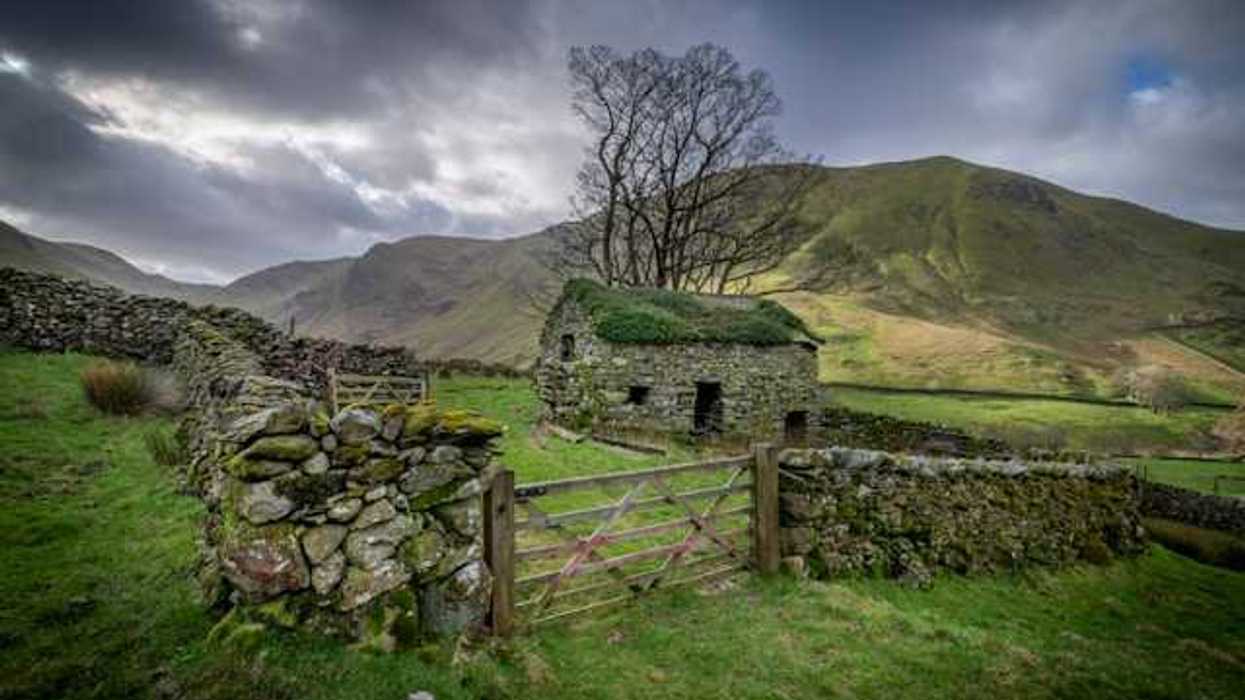 Stone house and fence on a cloudy day in a countryside setting