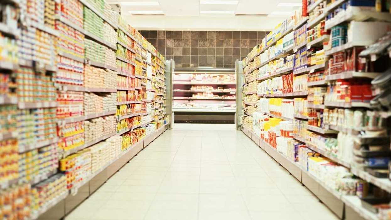 Supermarket aisle featuring shelves full of canned goods and packaged food