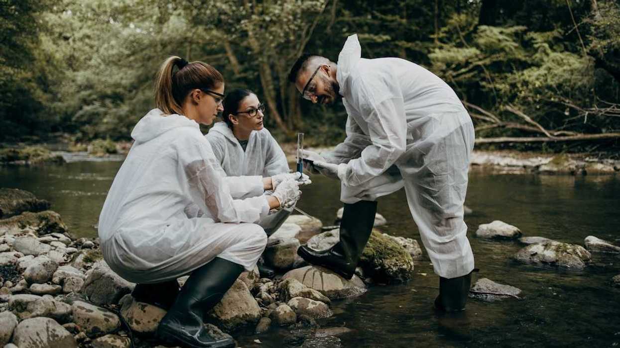 Team of three field researchers analyzing water samples from a river